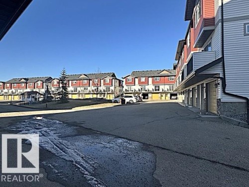 Multi-story residential buildings featuring red and white siding, individual balconies, and ground-level garages - #13 3751 12 Street, Edmonton, AB 