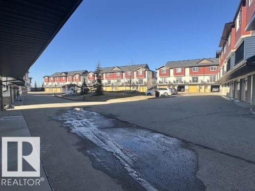 Townhome community featuring red siding, light-colored trim, and dark roofing - #13 3751 12 Street, Edmonton, AB 