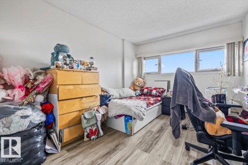 Room with wood-finish flooring, white walls, and a large window providing ample natural light - 77 8735 165 Street, Edmonton, AB 