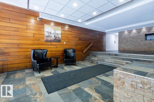 Entryway featuring multi-toned slate tile flooring, wood-panel accent wall, and stone veneer accent wall with integrated window - 77 8735 165 Street, Edmonton, AB 