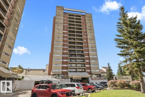 Multi-story building featuring numerous balconies, a main entrance canopy, and ground-level parking - 77 8735 165 Street, Edmonton, AB 