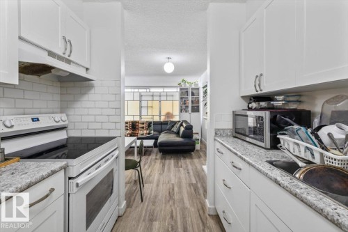Kitchen featuring white shaker-style cabinetry, a built-in electric range, white subway tile backsplash, and speckled countertops - 77 8735 165 Street, Edmonton, AB 