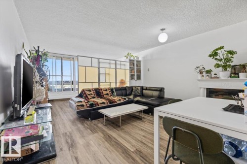 Living area featuring wood-finish flooring, a white mantelpiece with a fireplace insert, and built-in shelving - 77 8735 165 Street, Edmonton, AB 