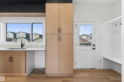 Utility area featuring a window, undermount sink with a matte black faucet, and white countertops - 