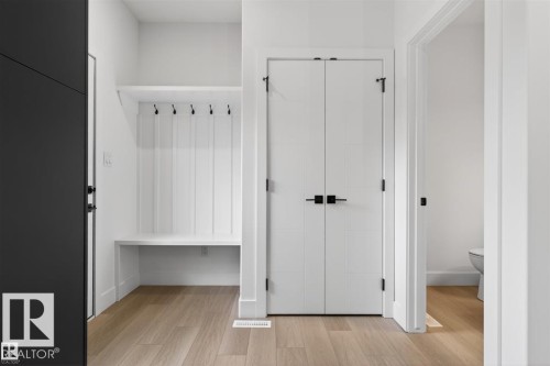 Entryway featuring wood-finish flooring, white shiplap wall paneling, a built-in bench, and black coat hooks - 41 River Birch Way, St. Albert, AB 