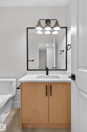 Bathroom vanity featuring a light wood-finish cabinet, white countertop, integrated sink, and matte black faucet - 