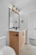 Bathroom vanity with a white countertop and integrated sink, complemented by a wood-finish cabinet and matte black hardware - 