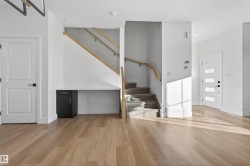 Open-concept entryway featuring light wood-finish flooring, a contemporary front door with horizontal lites, and a carpeted staircase with wood handrails - 