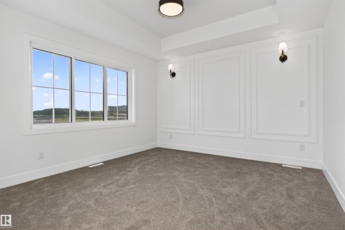 Spacious room featuring a tray ceiling, wall sconces, and decorative wall molding - 41 River Birch Way, St. Albert, AB - Indoor Photo Showing Other Room
