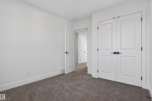 Bedroom featuring plush grey carpeting, white painted walls, white trim, and a white paneled closet with matte black hardware - 41 River Birch Way, St. Albert, AB - Indoor Photo Showing Other Room