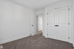 Bedroom featuring plush grey carpeting, white painted walls, white trim, and a white paneled closet with matte black hardware - 