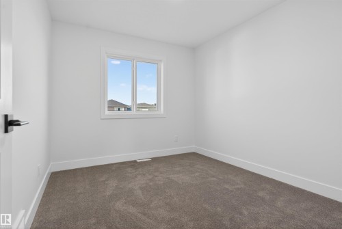 Neutral wall tones with a window and textured carpet flooring - 41 River Birch Way, St. Albert, AB - Indoor Photo Showing Other Room