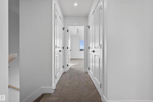 Hallway with carpet flooring, white walls, and multiple paneled doors with black hardware - 41 River Birch Way, St. Albert, AB - Indoor Photo Showing Other Room