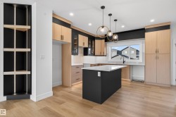 Contemporary kitchen with wood-finish flooring, a central island, and modern pendant lighting - 