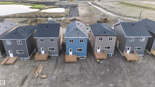 New construction residential property featuring a blue siding exterior, white-framed windows, dark shingle roofing, and a rear wood deck - 41 River Birch Way, St. Albert, AB - Outdoor