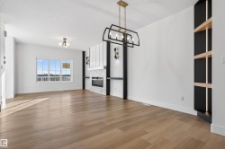 Open concept living space featuring wood-finish flooring, a contemporary linear fireplace with stacked stone surround, and an adjacent built-in shelving unit with integrated lighting - 