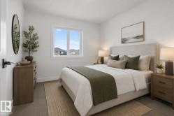 Bright bedroom featuring a large window, plush carpet flooring, white walls, and substantial baseboards - 