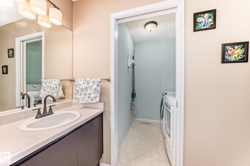 Bathroom vanity featuring an integrated white sink, dark cabinetry, and bronze-finish faucet - 11831 9 Avenue, Edmonton, AB 