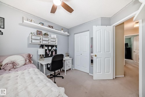 Carpeted interior room featuring a ceiling fan, a bi-fold closet door, and a paneled interior door - 11831 9 Avenue, Edmonton, AB 