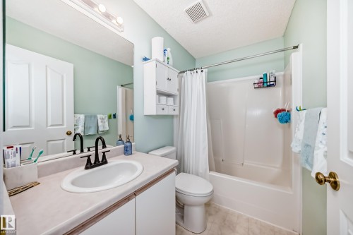 Bathroom featuring a white vanity with an integrated sink, dark bronze-finish faucet, and a large wall-mounted mirror - 11831 9 Avenue, Edmonton, AB 