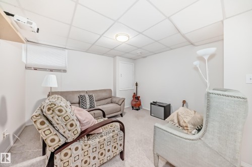 Carpeted room with a drop ceiling, white walls, and a single window with blinds - 11831 9 Avenue, Edmonton, AB 