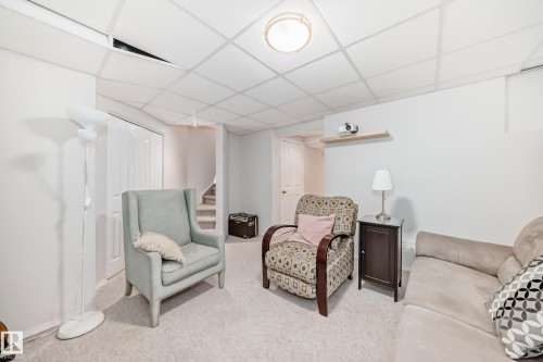 Carpeted room featuring white walls, a suspended ceiling with recessed lighting, and a floating wall shelf - 11831 9 Avenue, Edmonton, AB 