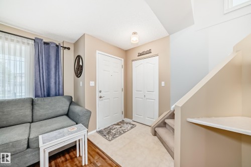 Entryway featuring a paneled door, bi-fold closet doors, and a carpeted staircase - 11831 9 Avenue, Edmonton, AB 