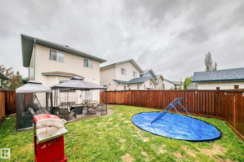 Expansive backyard featuring a privacy fence, a paved patio area, and a lush lawn - 11831 9 Avenue, Edmonton, AB 