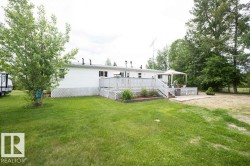 White siding exterior with a large wooden deck featuring lattice skirting - 