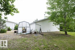 Side exterior of the property featuring white horizontal siding and a visible chimney vent - 