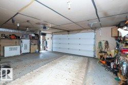 Garage with a white sectional overhead door, concrete flooring, and exposed ceiling joists - 