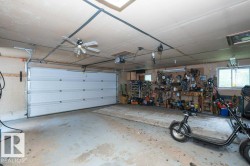 Spacious garage featuring a white panel garage door, concrete flooring, and ceiling-mounted fan - 