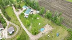 Expansive property featuring a main residence with a green roof, detached garage, multiple outbuildings, and extensive unpaved driveways - 