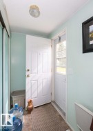 Entryway featuring a paneled door with brass hardware, a door with an integrated window, light blue painted walls, and textured flooring - 