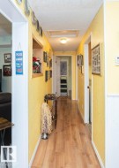 Hallway featuring wood-finish flooring, textured walls, and a ceiling-mounted light fixture - 