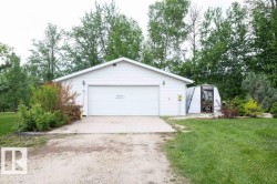 White vinyl-sided garage with a large overhead door and concrete driveway - 