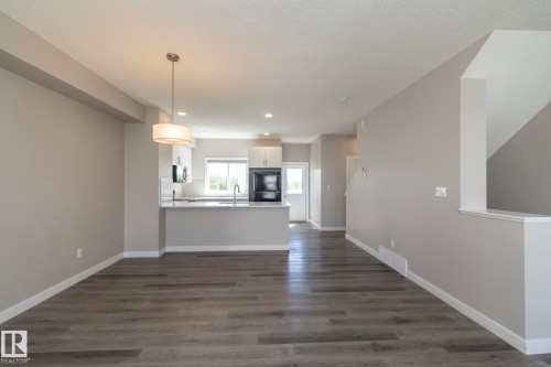 Open-concept living area featuring wood-finish flooring, a contemporary pendant light fixture, and recessed lighting - 2610 Maple Way, Edmonton, AB 