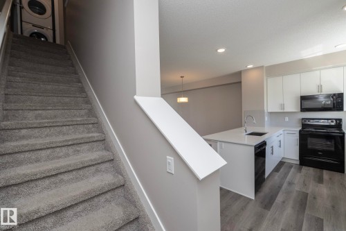 Staircase with gray carpeting and white trim, featuring a stacked washer and dryer unit - 2610 Maple Way, Edmonton, AB 