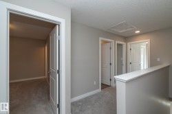 Upper-level hallway with multiple paneled doors, light gray wall paint, white trim, and gray carpet flooring - 