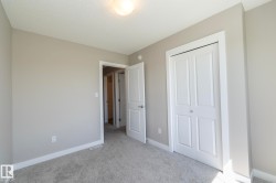 Neutral paint tones throughout this room, featuring light gray carpeting, white baseboards, and a bi-fold closet - 