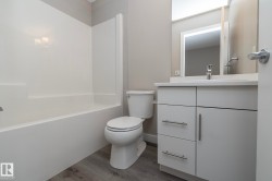 Bathroom featuring a white vanity with brushed nickel hardware, integrated sink, and white countertop - 