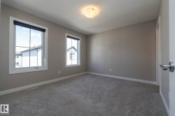 Spacious room featuring neutral paint, gray carpeting, dual windows with white trim, and a contemporary ceiling light fixture - 