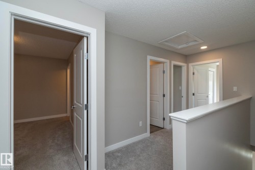 Upper-level hallway with multiple paneled doors, light gray wall paint, white trim, and gray carpet flooring - 2610 Maple Way, Edmonton, AB 