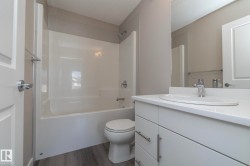 Bathroom featuring a white vanity with an integrated sink, chrome faucet, and expansive mirror - 