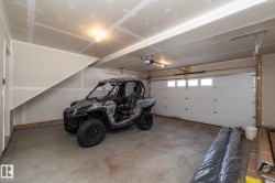 Spacious garage featuring a concrete floor, overhead lighting, and a white paneled garage door with windows - 