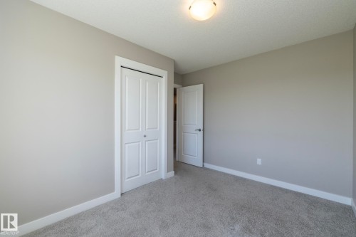 Neutral-toned room featuring a white bi-fold closet door, a white interior door, light grey carpeting, and white baseboards - 2610 Maple Way, Edmonton, AB 