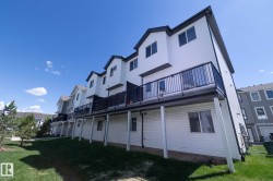 Contemporary townhome exterior featuring white horizontal siding and dark trim - 