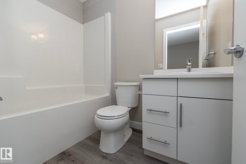Bathroom featuring a white vanity with brushed nickel hardware, integrated sink, and white countertop - 2610 Maple Way, Edmonton, AB 