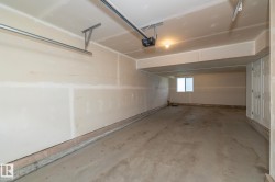 Spacious garage featuring a concrete floor, overhead lighting, and an automatic garage door opener - 