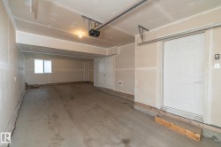 Spacious garage featuring a concrete floor, built-in storage closet, and an overhead garage door opener system - 
